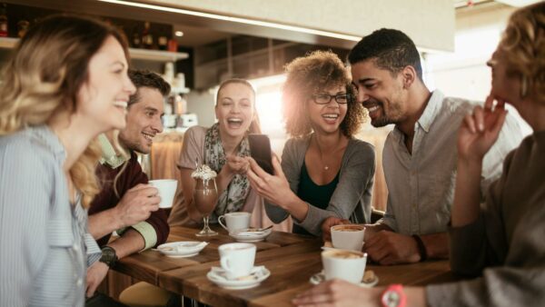 Eine Gruppe von Menschen sitzt um einen Tisch herum und trinkt Kaffee