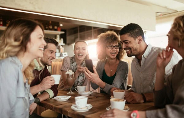 Un groupe de personnes est assis à une table et boit du café.
